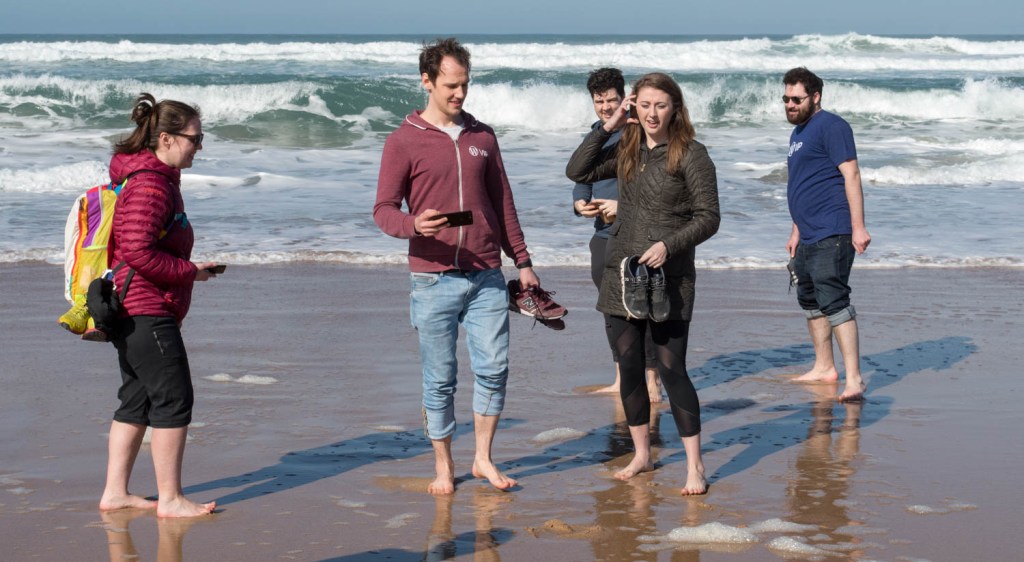 5 people on the VIP support team standing in front of waves on the beach