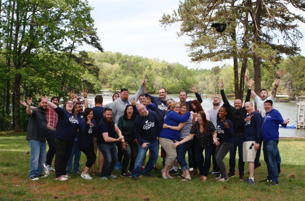 Personnel from WebDevStudios, emoting cheerfully and humourously near a body of water on a sunny day