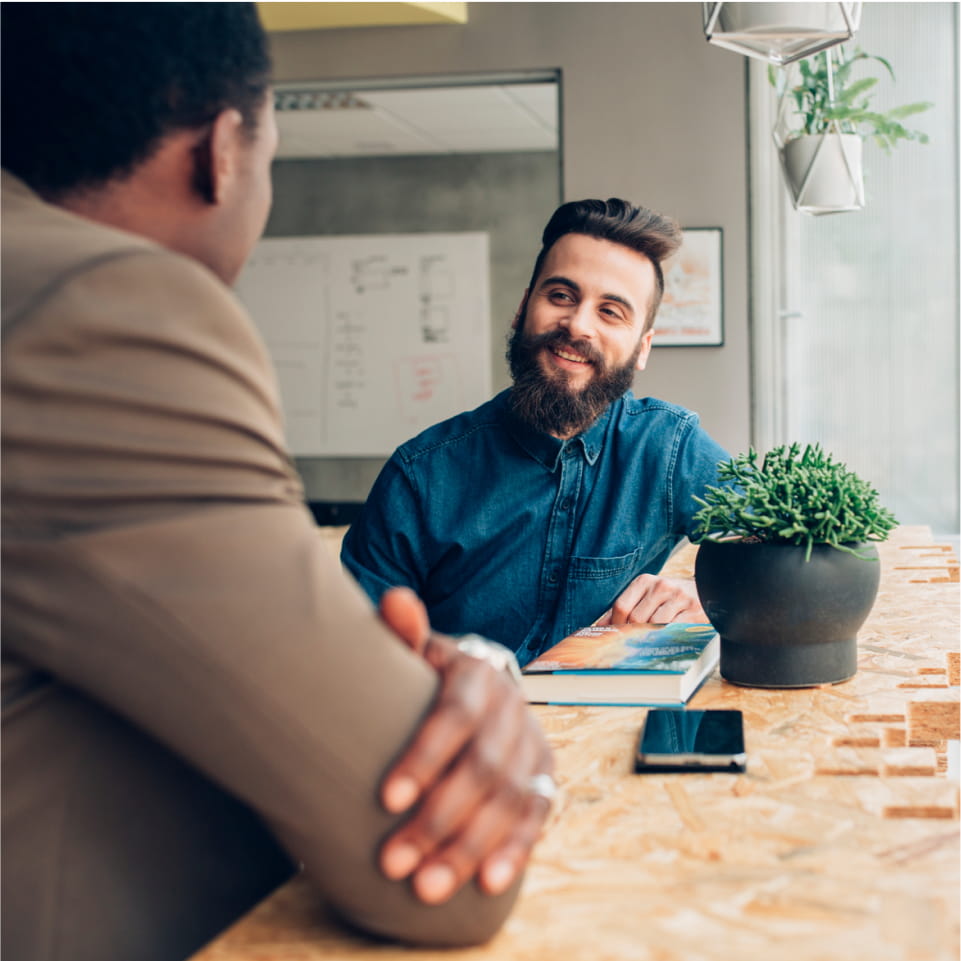 Two men conversing at table in office