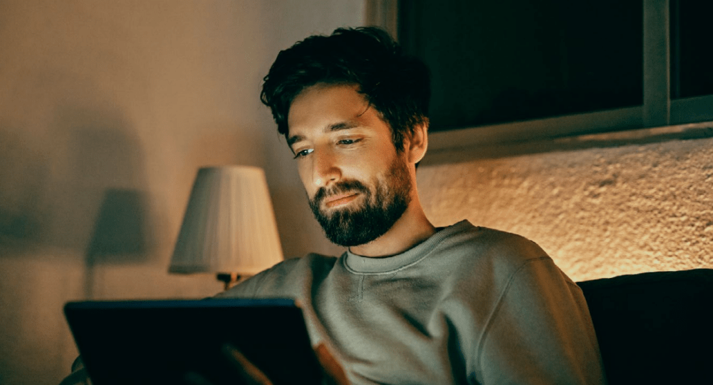 A person sitting on a couch and looking at a tablet