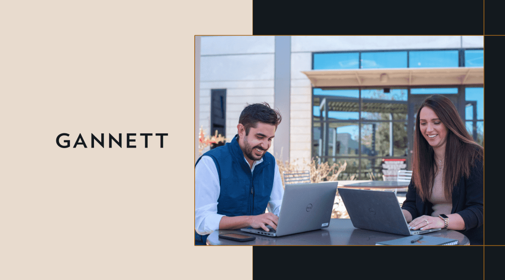 Two people working on laptops outside, next to the Gannett logo