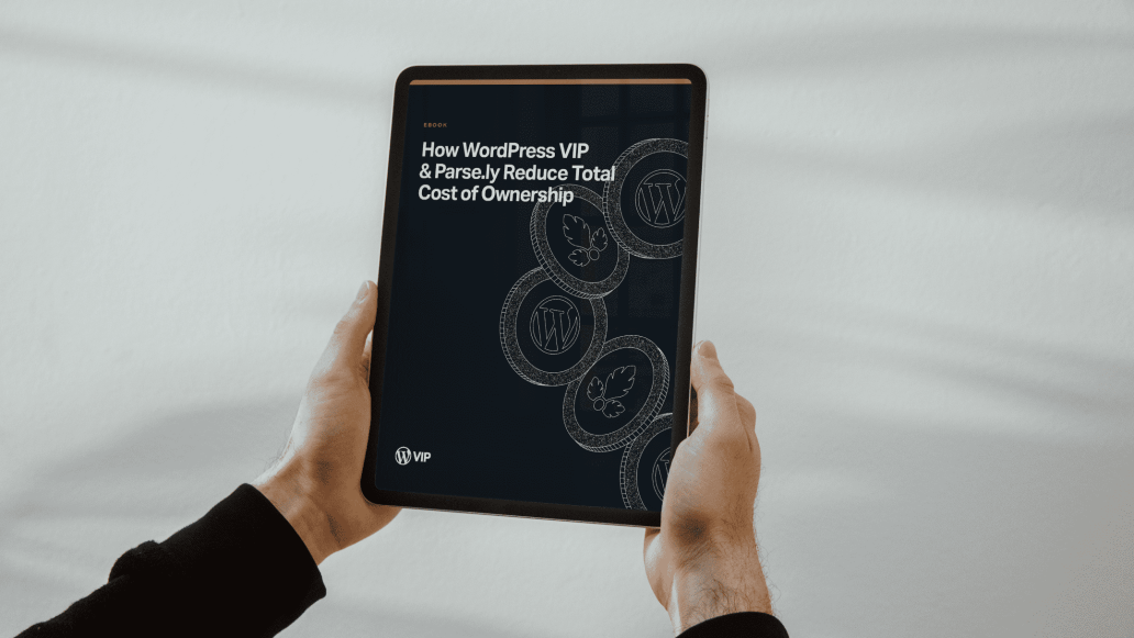 Hands holding tablet showing ebook 'How WordPress VIP & Parse.ly Reduce Total Cost of Ownership' with WordPress logos on dark background.