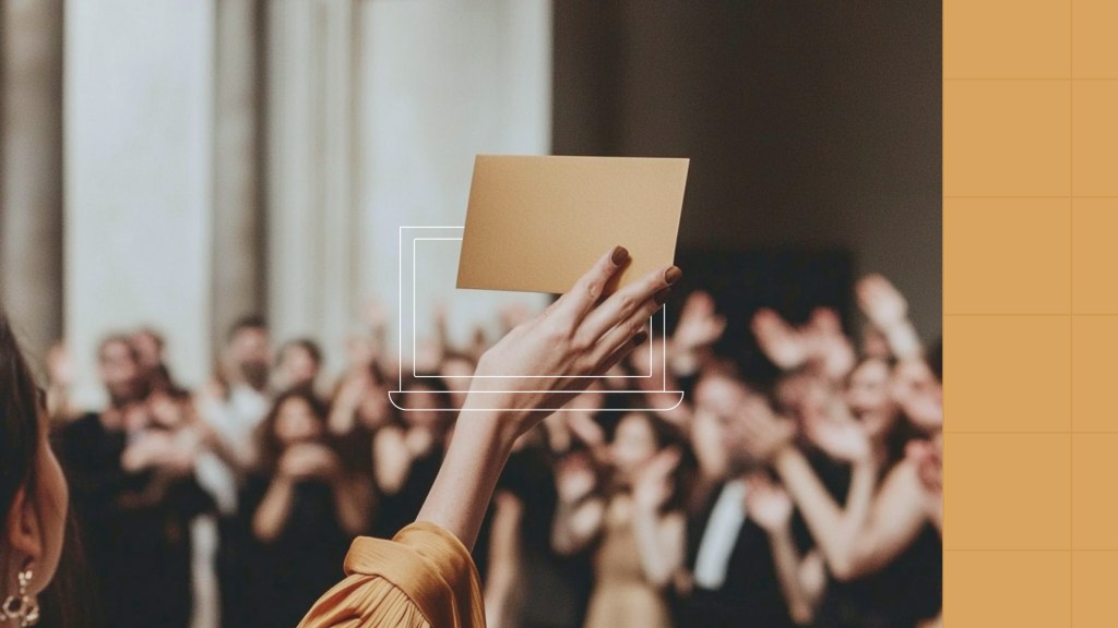 A person holds up a golden envelope, possibly announcing an award, in front of a crowd of people in a blurred setting. The image has a laptop outline overlay on the bottom center with a warm yellow background on the right.